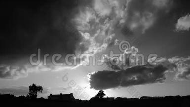 夕阳下的积云在乡村上空飞快地奔跑. 黑白延时镜头的云景。 房屋、农场